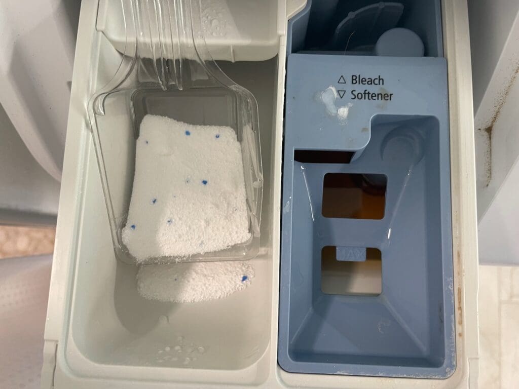 A white tub and sink with black tile.