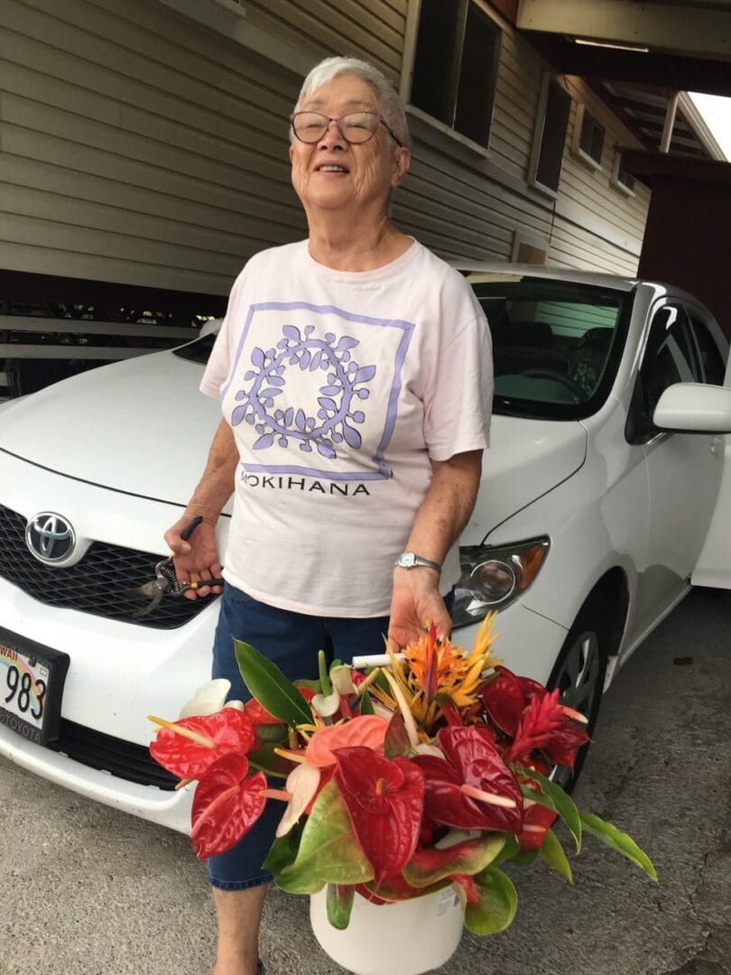 A man holding a basket of flowers in front of a car.