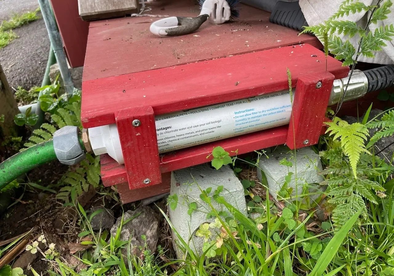 A red box sitting in the grass next to some plants.