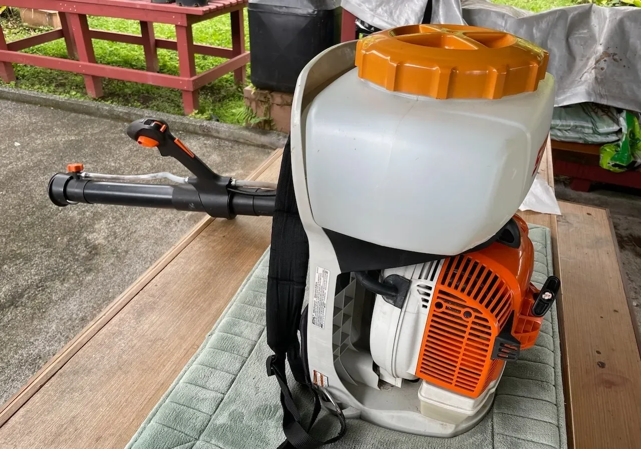 A backpack sprayer sitting on the ground.