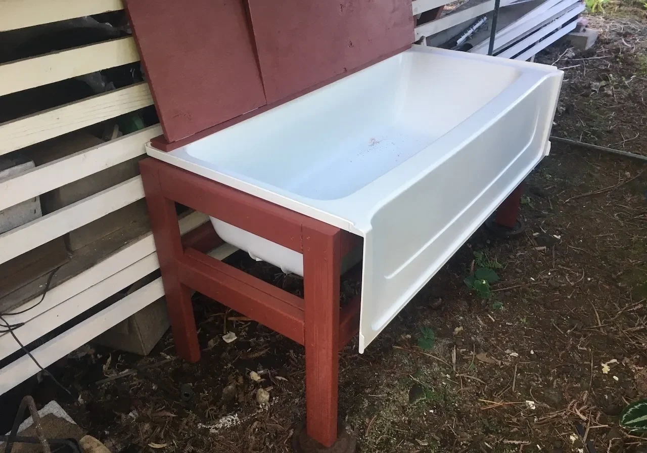 A white tub sitting on top of a wooden bench.